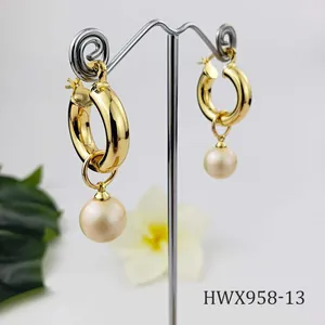 Detail of 18K gold chunky hoops with natural shell pearl pendants on a jewelry stand