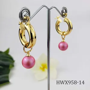 Detailed view of 18K gold plated hoop earrings with pink pearls on a metal stand