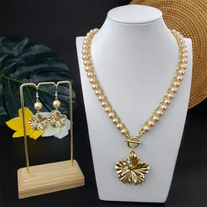Detailansicht der goldenen Blumenhalskette und Perlenohrringe auf einem Schmuckhalter