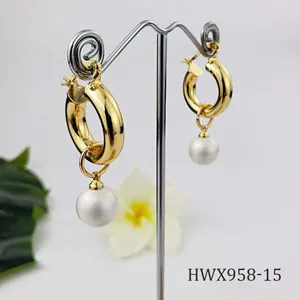 Detail of 18K gold-plated hoop earrings featuring natural shell pearl on a display stand