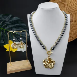 Detail eines Plumeria-Schmucksets mit grauen Perlen und kristallbesetzten Goldblüten