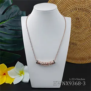 Hawaiian style carved tube pendant necklace in rose gold on a tropical display