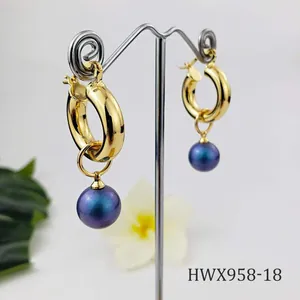 Detail view of 18K gold hoop earrings with iridescent purple shell pearl charms