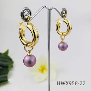 Detailed close-up of 18K gold hoop earrings with purple shell pearl drops on a metal display