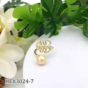 Detail van een gouden monstera blad ring met parel op een wit display voetstuk