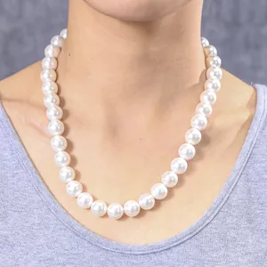Detail einer 12mm weißen Muschelperlenkette mit hohem Glanz am Hals eines weiblichen Models