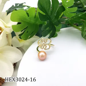 Detail van de gouden monstera blad ring met roze parel op witte displaystandaard