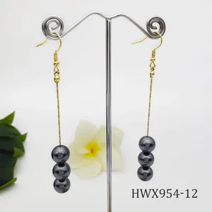 Detalle de pendientes largos chapados en oro de 14k con tres perlas gris oscuro elegantes