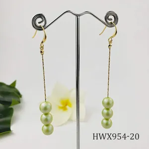 Detalle de pendientes largos bañados en oro de 14k con tres perlas naturales verde pistacho