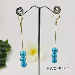 Vista detallada de pendientes largos bañados en oro de 14k con tres perlas azules