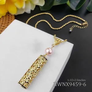 Detail van een bohemien gouden hanger met bloemig snijwerk en roze parel aan een gedraaide ketting