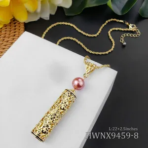 Detail van gouden holle bloemenhanger met roze parel aan een gedraaide ketting
