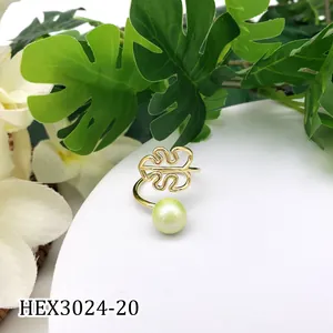 Detail van gouden monstera blad ring met lichtgroene parel op een wit voetstuk