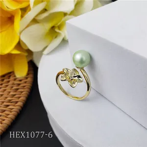 Primer plano del anillo de flor de frangipani con perla verde sobre pedestal blanco