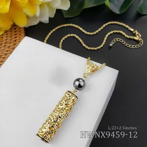 Detail van gouden holle cilinder hanger met zwarte parel aan gedraaide ketting