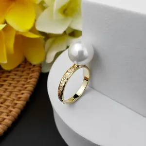 Dettaglio dell'anello dorato con incisioni floreali e una perla bianca tonda pura