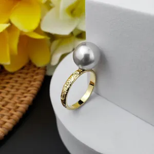 Anello vintage dorato con grande perla grigia tonda e incisione floreale su base