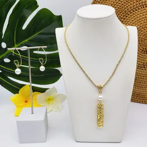 Parure de bijoux tropicaux dorés avec perles présentée avec frangipanier et feuilles