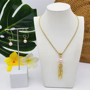 Détail du parure de bijoux dorés avec perles roses sur des feuilles tropicales