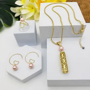 Détail d'un ensemble de bijoux dorés avec perles roses, pendentifs creux et boucles