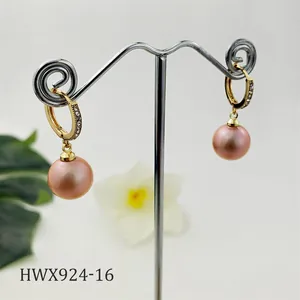 Dettaglio degli orecchini huggie dorati con zirconi cubici e perle di conchiglia rosa
