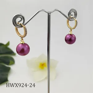 Dettaglio orecchini con perle viola e ganci dorati con zirconi incastonati per un look elegante