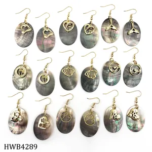 Collection of nine gold hook earrings with oval black shell pendants and Hawaii charms