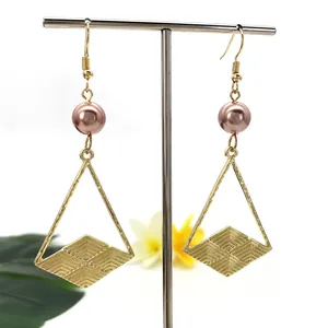 Orecchini geometrici dorati con perle rosa e ciondoli a triangolo su sfondo bianco