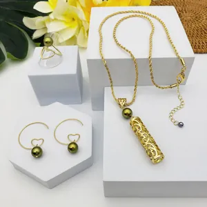 Détail du collier tube doré, boucles d'oreilles cœur et bague avec perles vertes