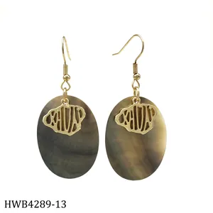 Detailed macro view of tropical black shell oval drop earrings with golden metal accents