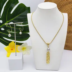 Détail de parure bijoux tropicaux dorés avec perles grises et pendentifs tube creux