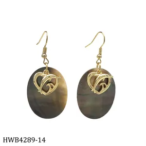 Close-up of tropical dangle earrings with natural black shell and golden dolphin heart