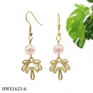 Details von goldenen Ohrhängern mit einer rosa Perle und einem Palmenanhänger