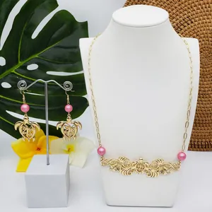 Détail du collier et des boucles d'oreilles tortue avec perles roses et fleurs tropicales