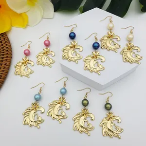 Détail de boucles d'oreilles plumes ondulées avec perles colorées et accents floraux dorés