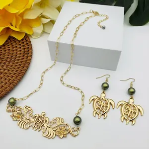 Détail d'un ensemble de bijoux tropicaux avec hibiscus, tortue et perles vertes