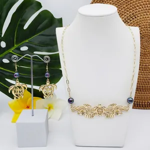 Détail d'une parure tortue dorée avec perles irisées et décor de fleurs tropicales