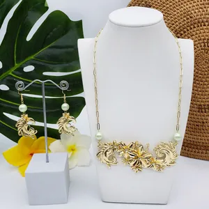 Détail de la parure dorée fleurie avec perles vert clair et motifs de vagues tropicales