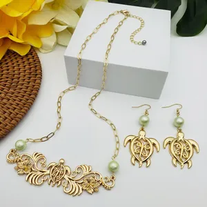 Gros plan détaillé sur l'ensemble bijoux tortue hawaïen doré avec perles vertes et fleurs