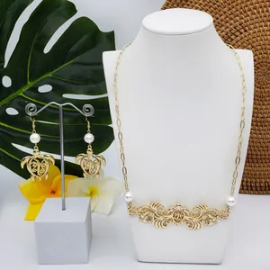 Parure de bijoux tortue dorée avec perles sur présentoir à feuilles tropicales