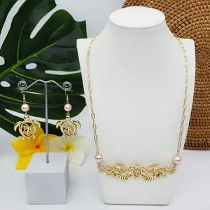 Parure de bijoux de style île avec motif tortue évidé et perles roses sur décor tropical