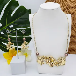 Détail de parure florale dorée avec perles brunes et cristaux sur feuille tropicale