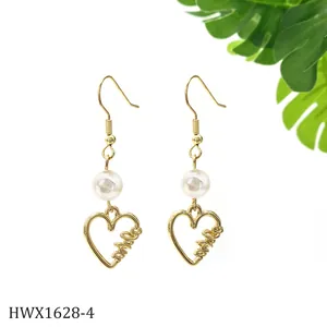 Detailansicht der goldenen Herz-Ohrhänger mit weißen Perlen und Love-Gravur im Makro