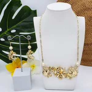 Parure de bijoux dorés avec fleurs et perles sur fond tropical avec feuilles de palmier
