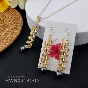 Détail de pendentifs spirale dorés avec perles sombres sur une carte de vœux Aloha