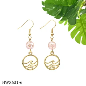 Details goldener Ohrhänger mit rosa Perlen und runden Anhängern im Wellendesign