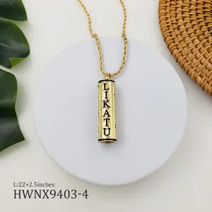 Détail d'un pendentif cylindrique doré avec gravure LIKATU sur une chaîne torsadée fine