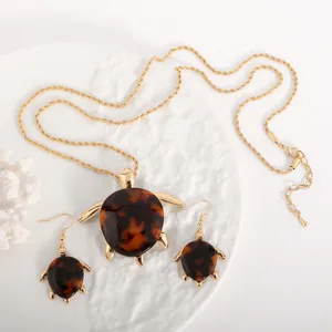 Detailaufnahme des goldenen Schildkröten-Schmucksets auf einem weißen Tablett