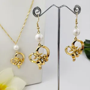 Dettaglio di parure collana e orecchini a cuore dorato con perle e accenti floreali