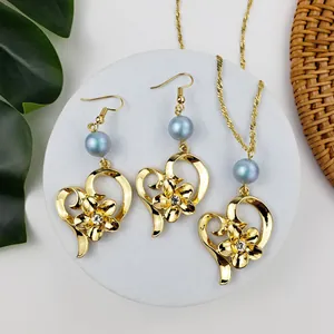 Set gioielli cuore plumeria dorato con perle azzurre e cristalli su pietra bianca